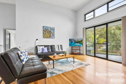 a living room with a leather couch and a table at Beach House Kendalls in Kiama