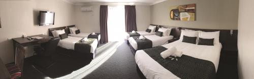 a hotel room with three beds and a window at Hunts Hotel Liverpool in Liverpool