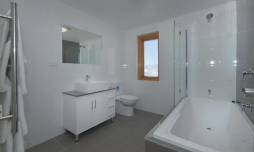 Smiggins Hotel & Chalet Apartments في بريشر فالي: حمام أبيض مع حوض ومغسلة ومرحاض