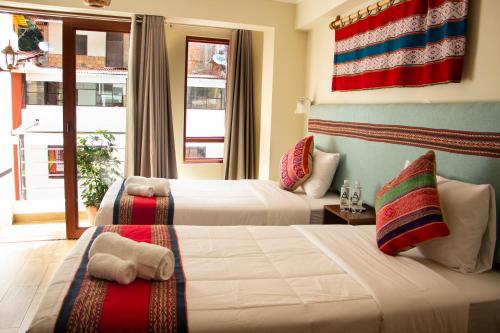 two beds in a hotel room with a flag on the wall at Rockrivers MachuPicchu in Machu Picchu
