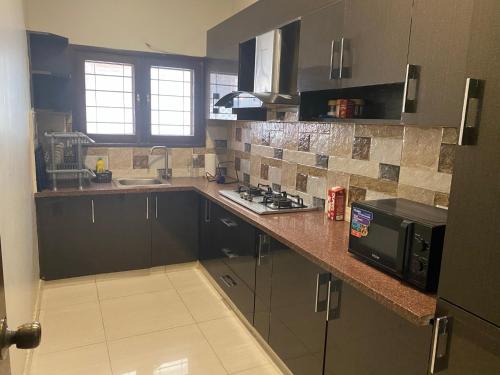 a kitchen with a counter with a microwave and a stove at Supreme Villa Block 6 Gulshan-e-iqbal Auto Generator in Karachi