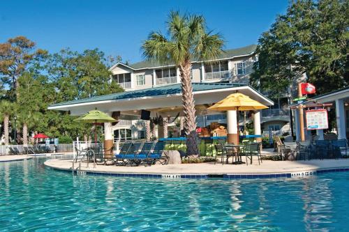 a pool with chairs and umbrellas in front of a hotel at Holiday Inn Club Vacations South Beach Resort in Myrtle Beach