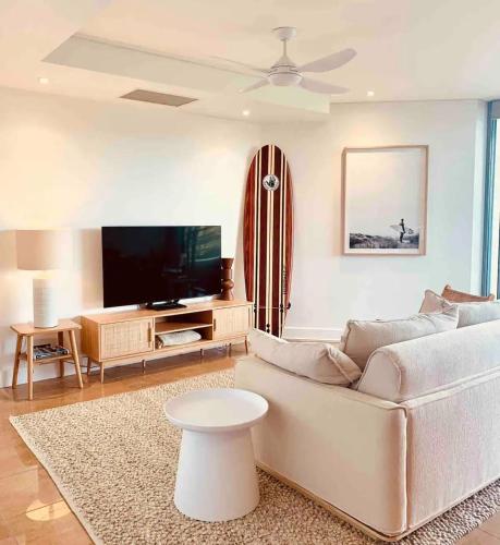 a living room with a couch and a flat screen tv at Cotton Beach Resort - Holiday Management in Kingscliff