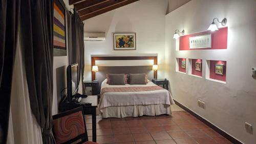 1 dormitorio con 1 cama y TV en Delvino Boutique Hotel en Salta