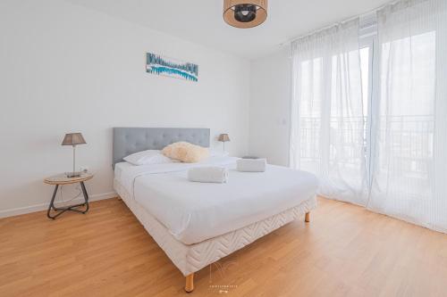 une chambre blanche avec un grand lit et une table dans l'établissement *Disneyland-Paris* 8 pers, Wifi, 2 parkings, à Chessy