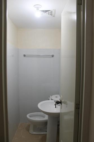 a white bathroom with a toilet and a sink at JUNLYN APARTELLE in Panglao Island