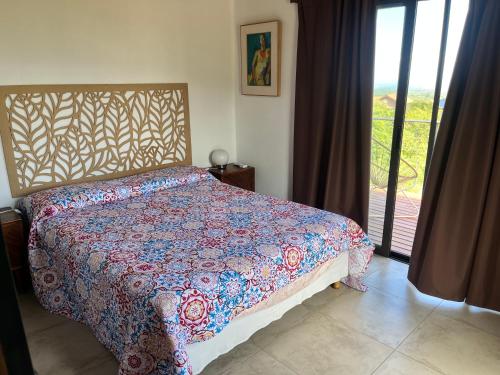 a bedroom with a bed with a colorful comforter at Flor Silvestre in Carpintería