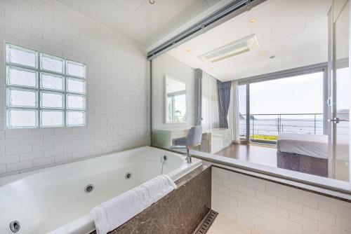 a bathroom with a tub and a bed and a window at The Grand Sumorum in Seogwipo