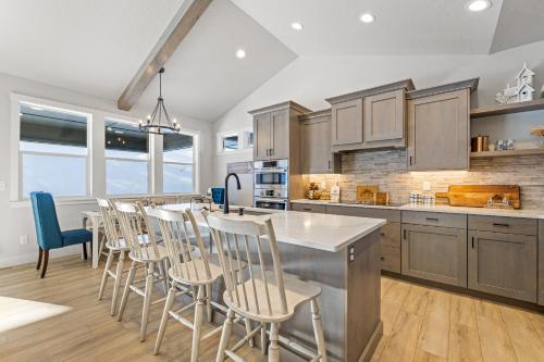 a kitchen with a bar with chairs and a table at New Mountain Bluebird - walk to lake, golf, and town - game rm - family friendly - sleeps 14 in Cascade