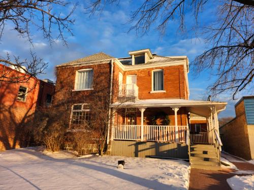 an old brick house with a porch in the snow at Stone House Kenora in Kenora