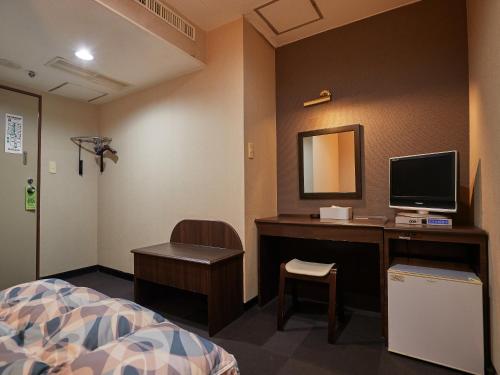 a bedroom with a desk with a computer and a bed at Hotel Yamanouchi in Naha