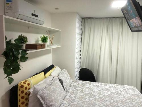 um quarto com uma cama com almofadas e uma janela em Apartamento c/ Suíte DF Plaza - Vista Espetacular em Brasília