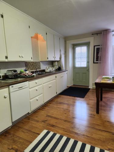 a kitchen with white cabinets and a wooden floor at Stone Carriage House in Picton