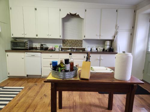 a kitchen with a table with a basket of bottles at Stone Carriage House in Picton