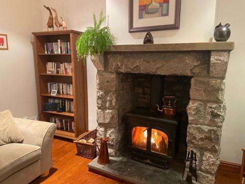 a living room with a stone fireplace with a fire at Barnhaven, Lake District National Park in Brigsteer