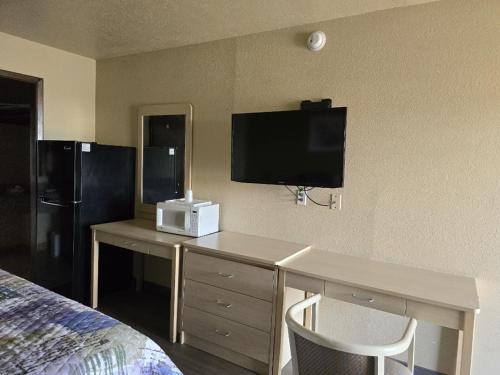a hotel room with a desk and a tv on the wall at Lodge USA Motel in Guymon