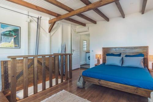 een slaapkamer met een blauw bed in een kamer bij Cap Sud Bungalow du bourg près de la mer in Sainte-Anne