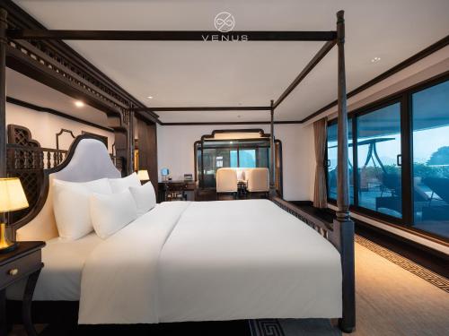 Schlafzimmer mit einem großen weißen Bett und Fenstern in der Unterkunft Venus Halong Cruises in Hạ Long