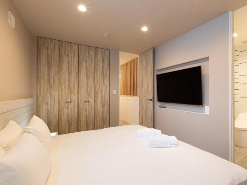 een slaapkamer met een wit bed en een televisie bij Olaf House in Niseko