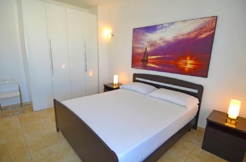 レウカにあるAttico del sole e del mareのベッドルーム(白い大型ベッド、ランプ2つ付)