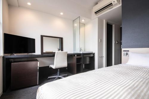 a bedroom with a bed and a desk with a computer at Hotel Vista Kumamoto Airport in Ozu