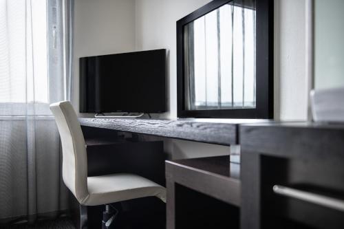 a computer desk with a computer monitor and a chair at Hotel Vista Kumamoto Airport in Ozu
