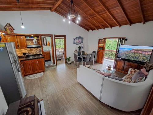 a living room with a white couch and a kitchen at Casa familiar vacacional in Jardin