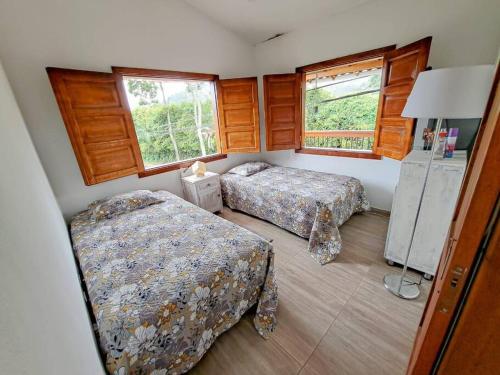 a bedroom with two beds and two windows at Casa familiar vacacional in Jardin