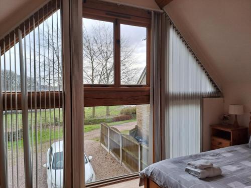 a bedroom with a bed and a large window at Orchard Cottage in Bradley in the Moors