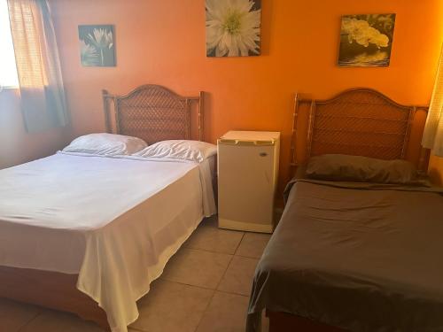 2 camas en una habitación con paredes de color naranja en Coco Hotel and Hostel en Sosúa