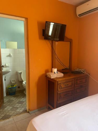 um quarto com uma cama e uma televisão numa cómoda em Coco Hotel and Hostel em Sosúa