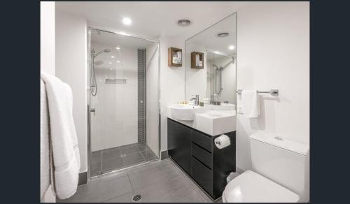 uma casa de banho branca com um lavatório e um chuveiro em Discover urban bliss in our 1-bedroom King bed apartment! City views and cultural gems em Brisbane