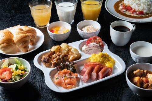a table with plates of breakfast foods and drinks at Hotel Vista Kumamoto Airport in Ozu