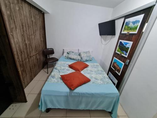 a bedroom with a bed with blue sheets and red pillows at POUSADA DO HOSTEL in Jacobina