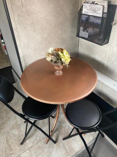 een houten tafel met een vaas met bloemen erop bij Tiny RV Stone pool Inn, Pets stay free, Zion National Park, your private Oasis! in St. George