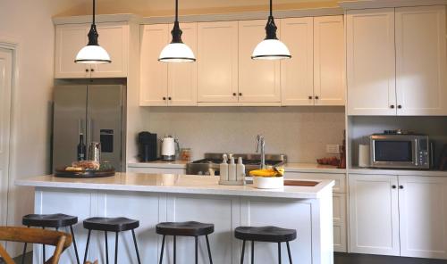 a kitchen with white cabinets and bar stools at Barossa Bed & Breakfast in Tanunda