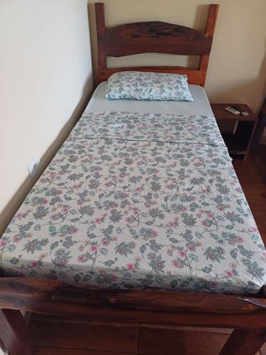a bed in a room with a floral bedspread on it at Pousada Estância Mineira in Campo Grande