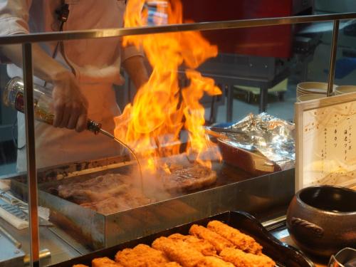 a man is cooking food on a grill with flames at Hakone Kowakien Hotel in Hakone