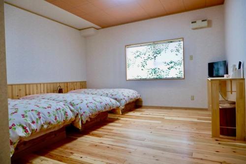 1 dormitorio con 2 camas y ventana en Yakushima Pension Ichigoichie, en Yakushima