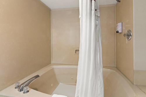 a bathroom with a bath tub with a shower curtain at Red Roof Inn & Suites Monroe, NC in Monroe