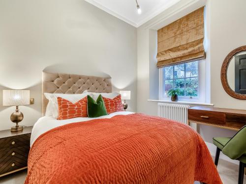 a bedroom with a bed with orange and green pillows at Old Bank House in Barnard Castle