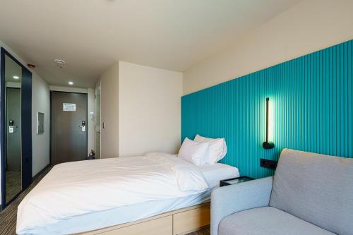 a bedroom with a white bed and a blue wall at Little Prince Hotel&Condo in Gunsan