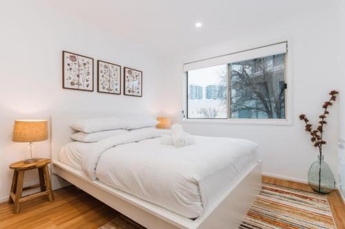 Un dormitorio blanco con una cama grande y una ventana en Lakeside 3-Bed Apartment with Jacuzzi, en Belconnen