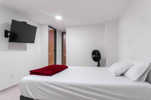a white bed with a red blanket and a flat screen tv at Cómodos apartamentos cerca al metro de Medellín in Medellín