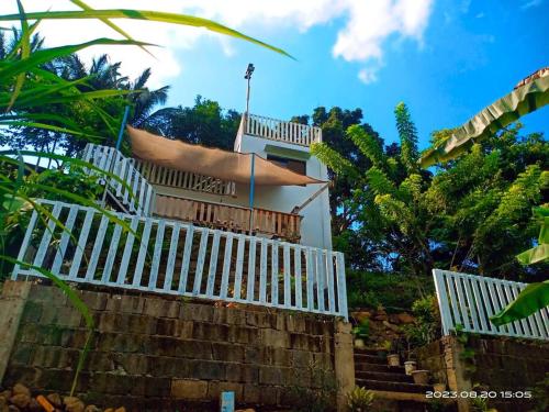 Overlooking Vacation house by Magayon Viewpoint في تاناي: منزل به سياج أبيض ودرج