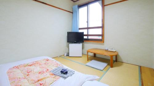 a hospital room with a bed and a tv at Business Hotel Furusato in Ibusuki