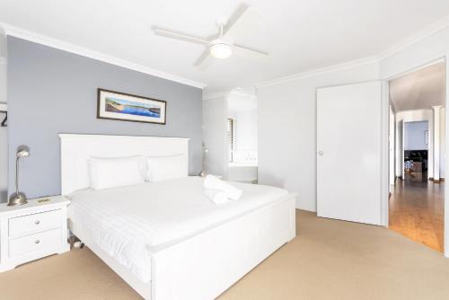 a white bedroom with a white bed and a ceiling fan at Singleton Impressions - EXECUTIVE ESCAPES in Singleton