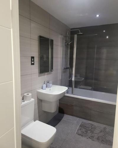 a bathroom with a toilet and a sink and a tub at 2 Bedrooms 2Baths 3Toilets near Excel City Airport O2 Sleeps up to 5 in London