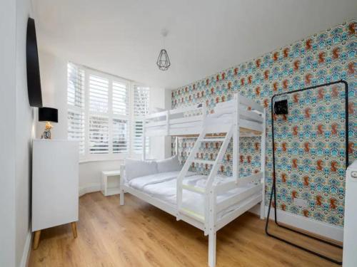 um quarto branco com um beliche e uma parede em Pass the Keys Modern and Bright Home Minutes From Central London em Londres