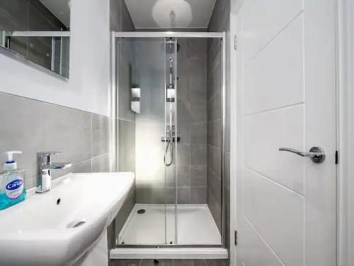 uma casa de banho branca com um chuveiro e um lavatório. em Pass the Keys Modern and Bright Home Minutes From Central London em Londres